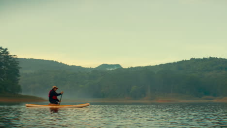 man kayaking on a misty mountain lake