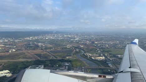 A-sprawling-cityscape-seen-from-an-airplane-wing-during-daytime,-aerial-view