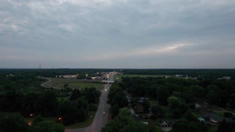 Luftdrohne,-Die-Sich-Vorwärts-Bewegt,-Schoss-über-Die-Autobahn,-Die-Durch-Eine-Kleine-Stadt-Mit-Vorbeifahrenden-Autos-Während-Der-Abendzeit-Führt