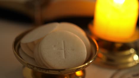 communion hosts in twilight illuminated by the light of a lit candle