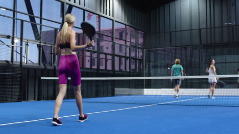 Man playing padel tennis on indoor court, hitting ball with racket on blue indoor court