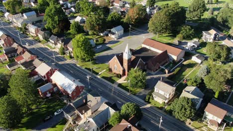 órbita-Aérea-De-Una-Pequeña-Ciudad,-Pueblo-En-Estados-Unidos,-Casas-E-Iglesia-Durante-La-Hora-Mágica-Del-Verano-Mientras-Pasa-El-Tráfico,-Disparo-De-Drones