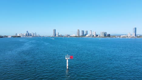 speed boat travelling towards a navigational beacon with a city skyline rising above in the distant