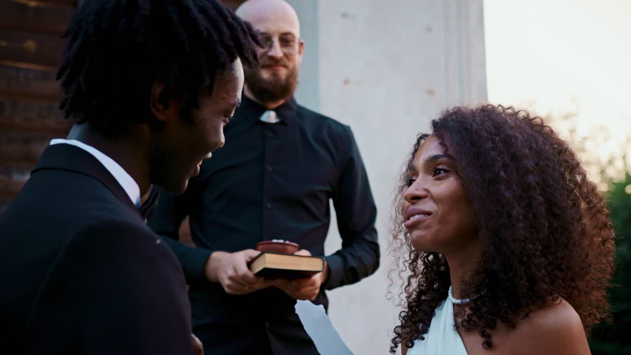 Um casal inter-racial se casando em uma cerimônia de casamento ao ar livre
