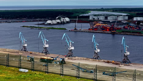 row of large harbor cranes standing ready for work on the dockside of ks terminal, a bulk cargo handling facility within the industrial landscape of the port of riga, latvia