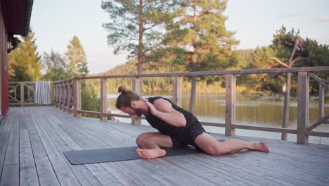 hombre haciendo ejercicios de yoga en la veranda al lado del lago en noruega