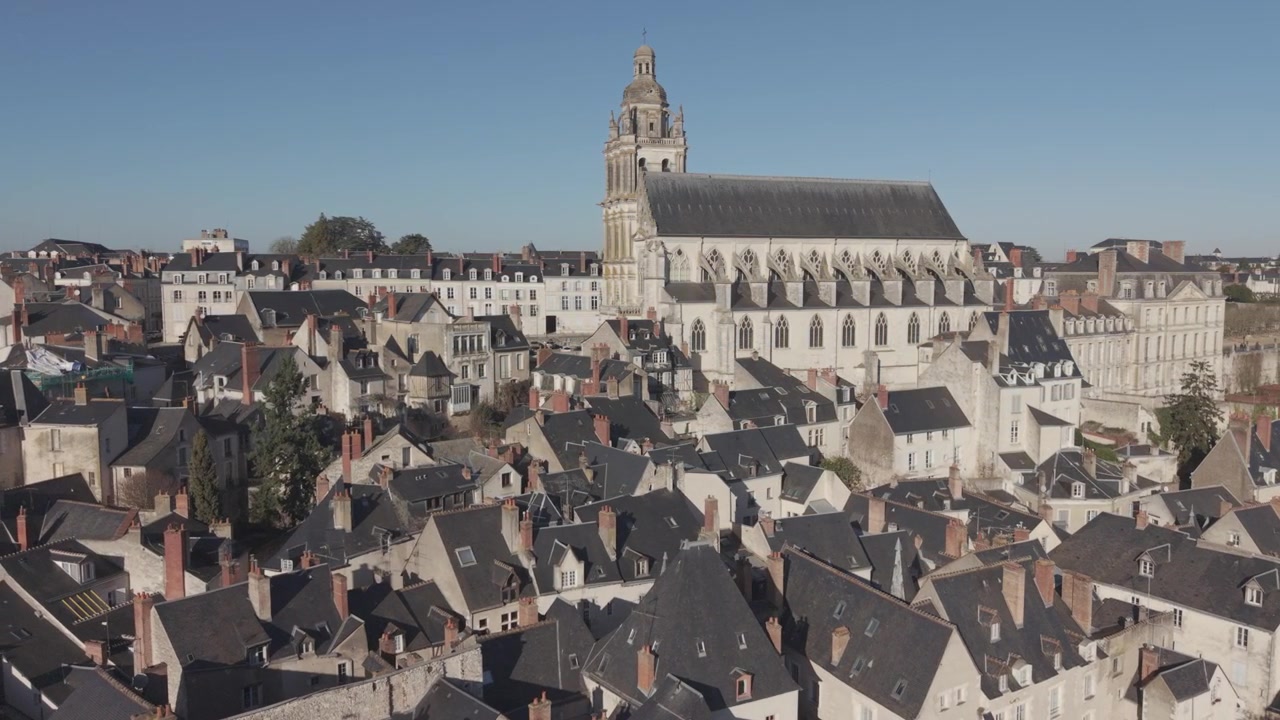 Una vista aerea mostra l'alta guglia e il profilo del tetto della Cattedrale di Blois che si ergono sopra i tetti circostanti della città.