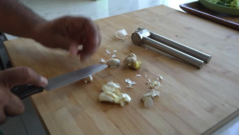 hands peeling garlic and ginger on a cutting board