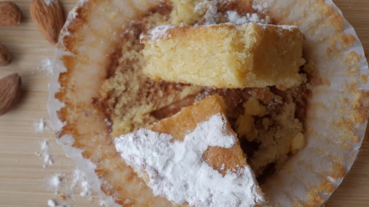 Almond cake slice with powdered sugar on a wooden table, rustic feel