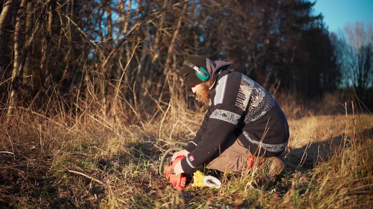 A Man is Examining His Chainsaw - Static Shot