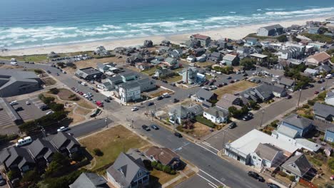 Drone-shot-of-cars-driving-on-the-streets-of-a-small-coastal-town-in-Oregon-with-the-Pacific-Ocean-in-the-background