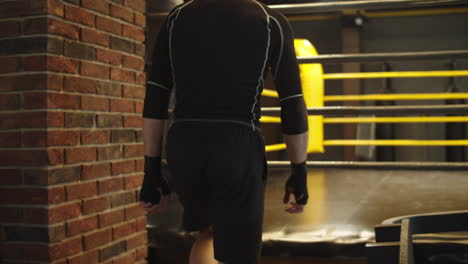 sporty fit man preparing for fight in club. boxer walking up stairs on ring