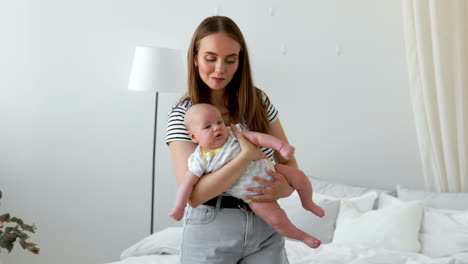 the concept of a modern young family in a white apartment. mom puts the baby to bed singing him a lullaby