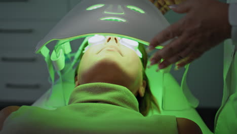 Frau-Liegt-In-Einer-Phototherapie-Klinik,-Nahaufnahme.-Kosmetikerin-überprüft-LED-Lichtmaske.