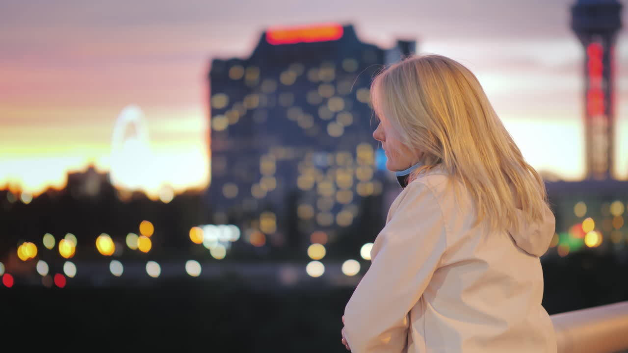 una mujer pensativa se encuentra en un puente en la ciudad nocturna con el telón de fondo de luces brillantes y miradas
