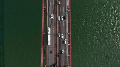 Vogelperspektive-Von-Oben-Nach-Unten-Auf-Den-Starken-Verkehr-Auf-Mehrspurigen-Straßen-In-Der-Hauptverkehrszeit.-Autobahnbrücke-über-Gewelltes-Wasser-Von-Drohnenkamera.-Lissabon,-Hauptstadt-Von-Portugal.