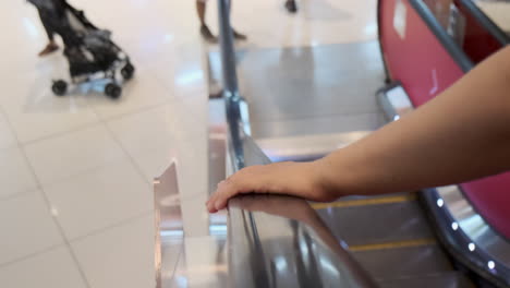 persona sosteniendo la barandilla de la escalera mecánica en un centro comercial