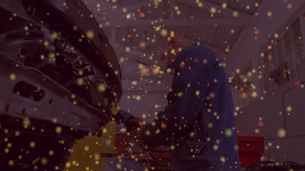 Mechanic operating power tool in automotive workshop, featuring floating red and golden sparks