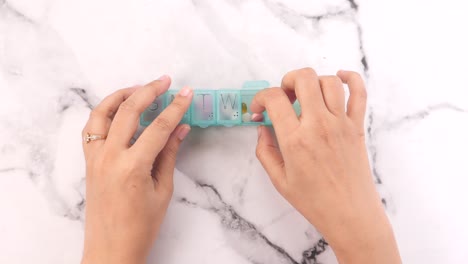 woman's hands using a weekly pill organizer