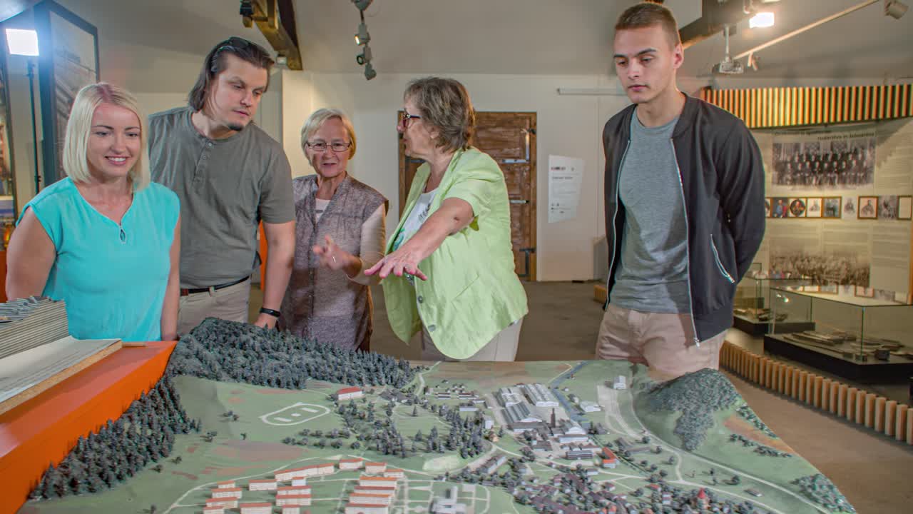 group of people view a scale model of the town. Guide explain the details