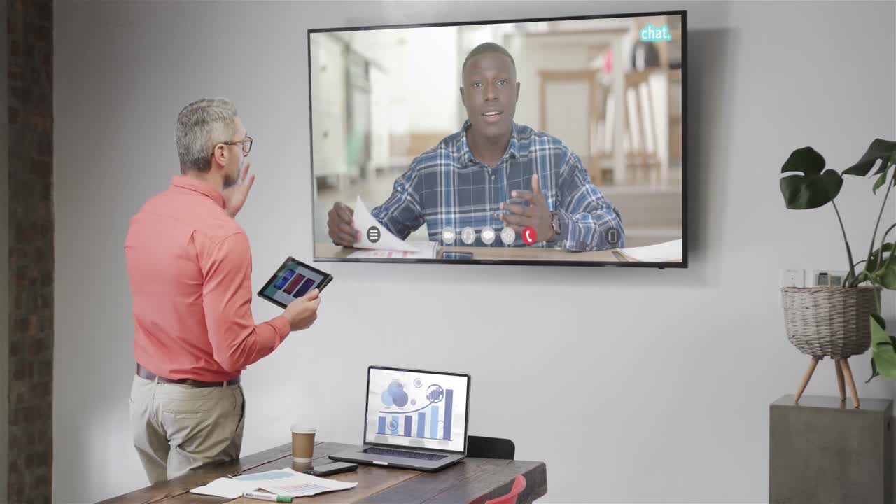 Caucasian businessman on video call with african american male colleague on tv screen