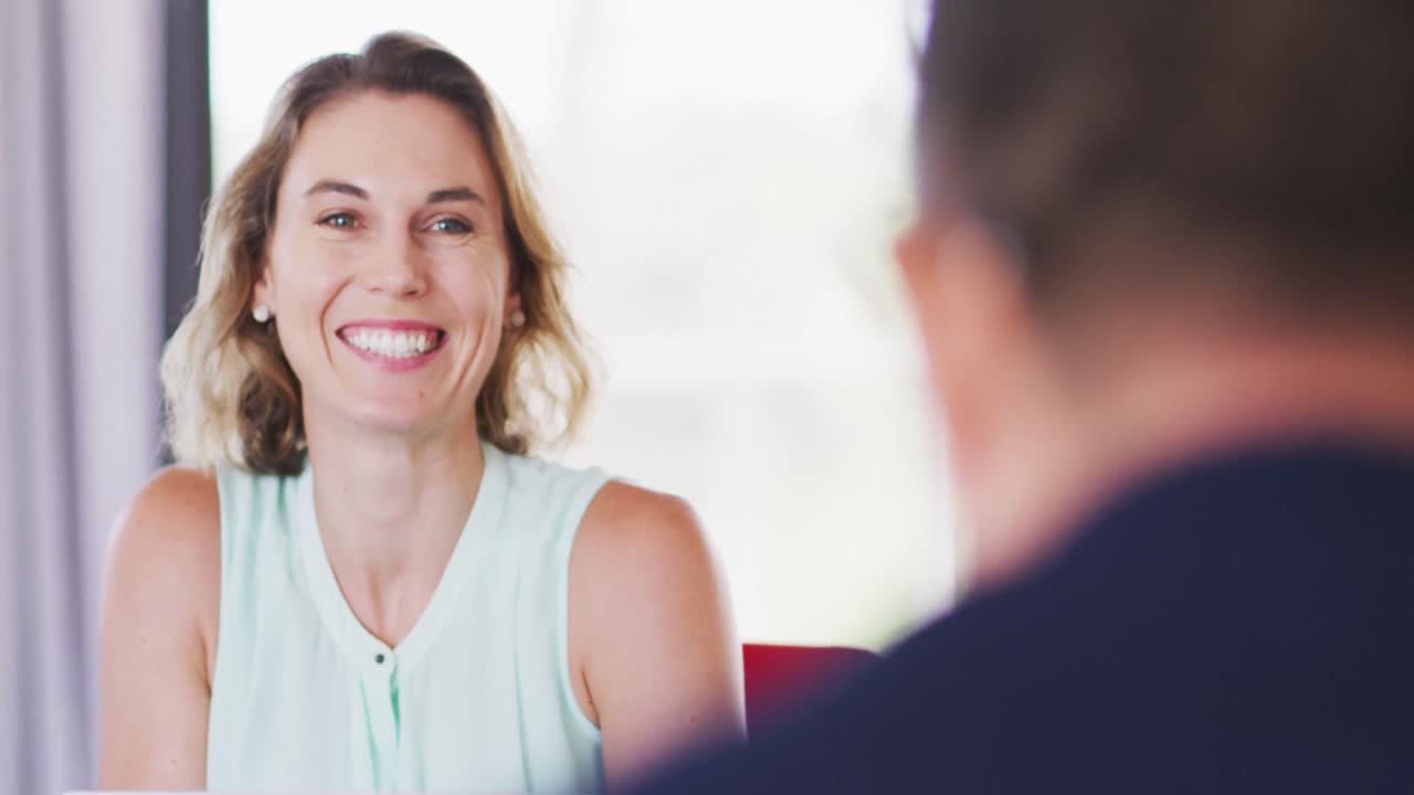 Una professionista che sorride mentre parla con i suoi colleghi in un ufficio moderno, al rallentatore.