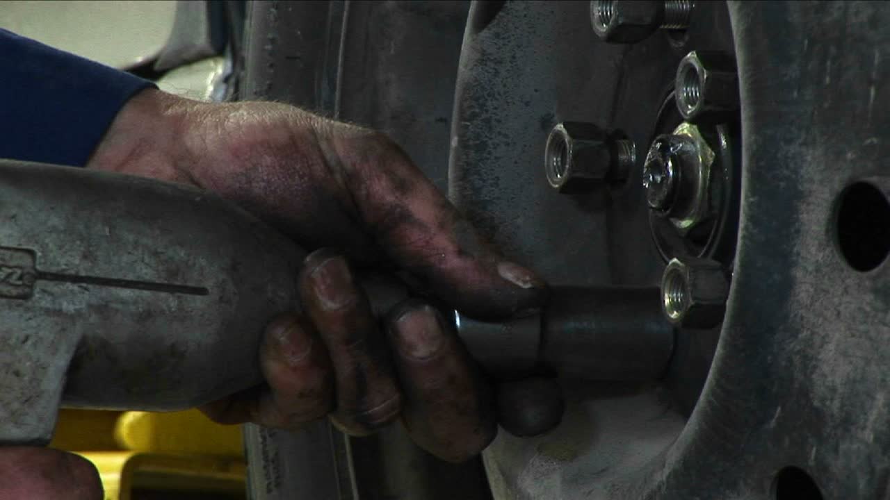 un mecánico aprieta las tuercas con una herramienta eléctrica en este primer plano