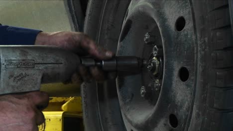 a mechanic tightens lugnuts with a power tool in this closeup