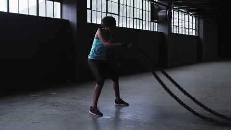 african american woman exercising battling ropes in an empty urban building