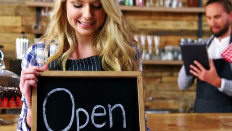 Smiling-waitresses-holding-open-sign-board