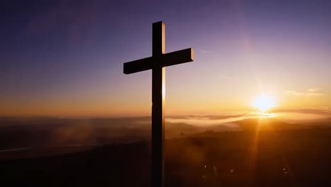 das sonnenlicht, das hinter einem bergkreuz aufsteigt, erzeugt eine atemberaubende silhouette über einem meer von wolken, die gefühle der hoffnung und des glaubens hervorruft.