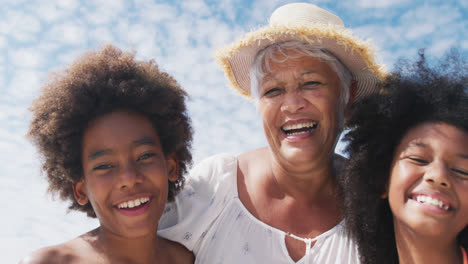 Retrato-De-Una-Mujer-Mayor-De-Raza-Mixta-Con-Nietos-Sonriendo-En-La-Playa