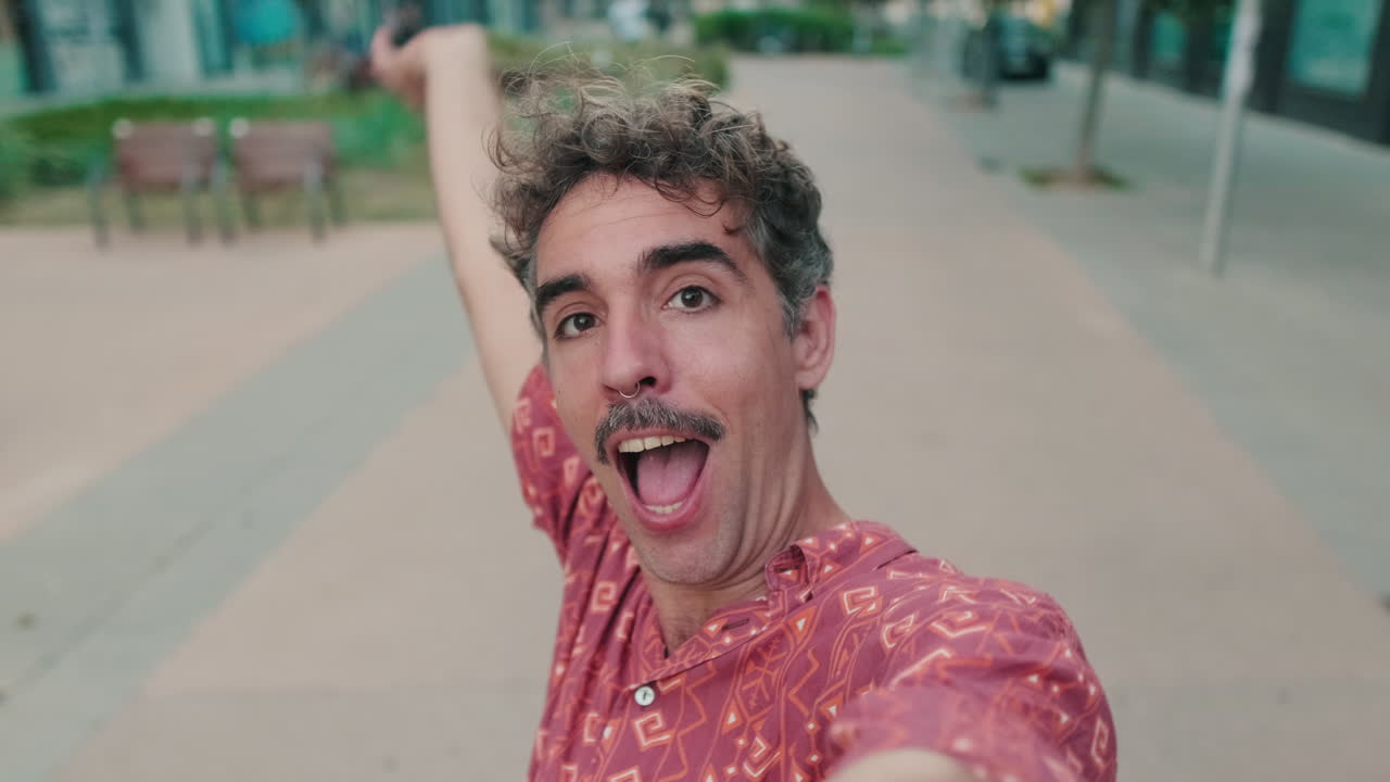 Homem divertido com bigode e piercing no nariz posando para vídeo selfie