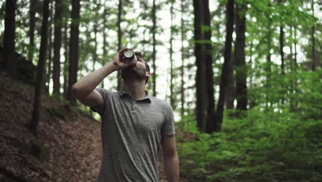 Caucasian-man-walking-in-forest,-holding-and-drinking-coffee-from-paper-cup,-front-view