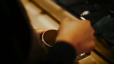 close up over the shoulder shot of barista pouring milk on coffee to make a caffè latte