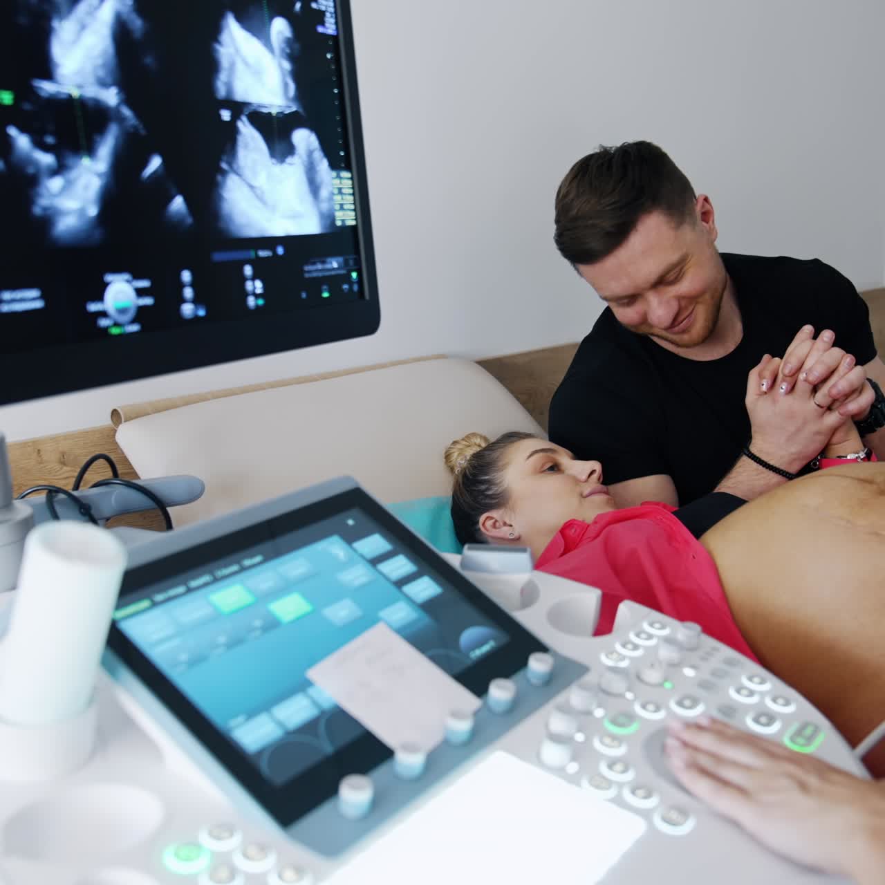 Woman on the last stages of pregnancy is checked on the ultrasonic equipment. Caring man supporting his husband