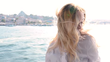 slow motion:beautiful girl poses over galata bridge and enjoys view of bosphorus and suleymaniye mosque in istanbul,turkey