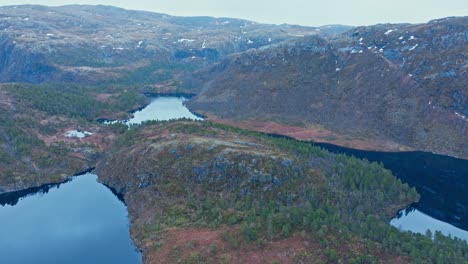 a scenic view of kattavatnet lake, nestled among rugged hills and forested terrain in roan, trøndelag, norway - aerial pullback shot