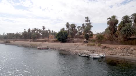 small fishing town next to the nile river with fishing boats and palm trees, egypt.