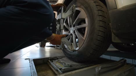 mecánico de automóviles instalando sensor durante el ajuste de la suspensión y el trabajo de alineación de las ruedas del automóvil en la estación de servicio de reparación.