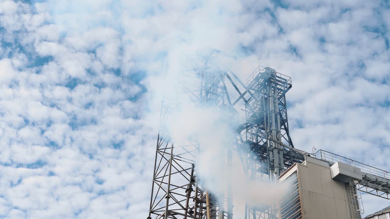 Pollution from industry. White smoke from industrial grain dryer on sky background. Elevators for storage and further processing of grain