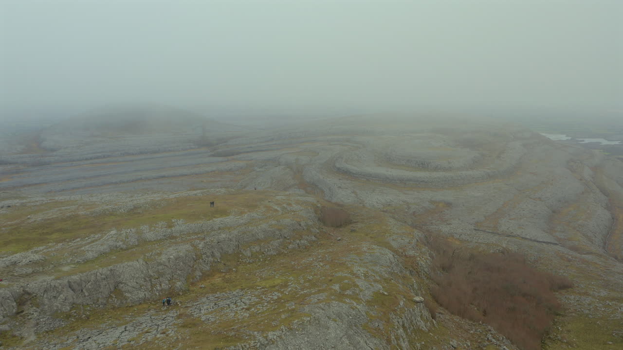 Aerial tracking shot over Mullaghmore Peak through mist with hikers enjoying the views. Ireland