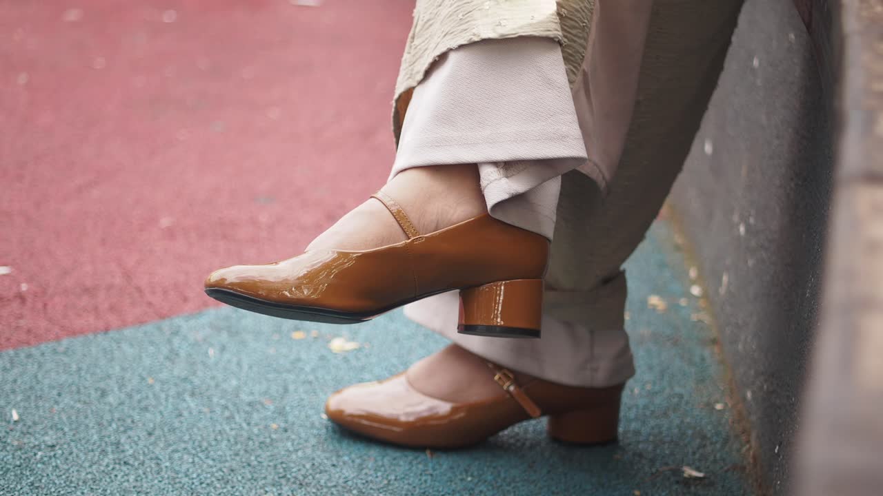 Close-up of person wearing brown patent leather Mary Jane shoes