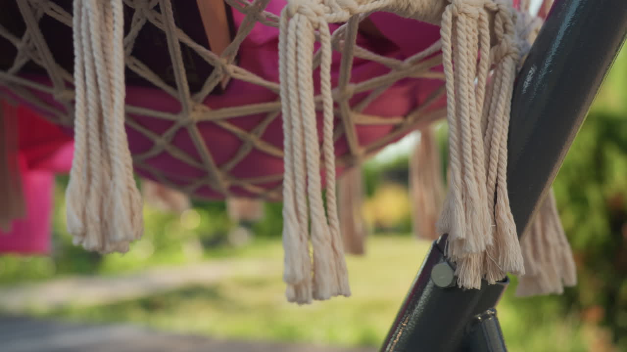 Relaxing Outdoor Decor, Sunlit Boho Hammock With Tassels, Textured Cotton Ropes Sway Gently In Bright Sunshine, Rustic Patio Setting Featuring Tasseled Hammock And Textured Macrame Details