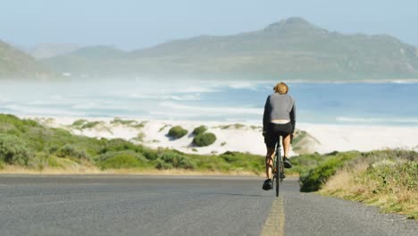 Rückansicht-Eines-Triathleten,-Der-Auf-Der-Landstraße-Radelt