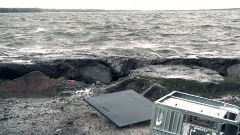 computer discarded on the shore of a stormy lake.