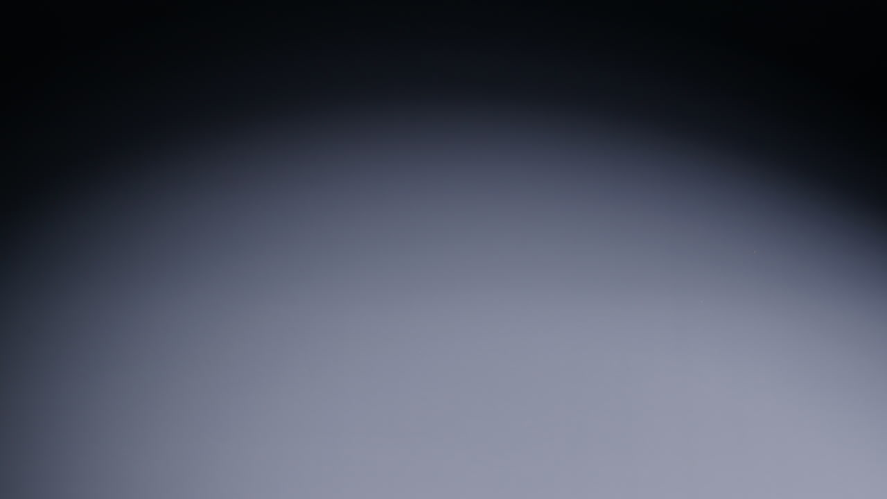 Slow-motion wide shot of white die rolling from screen right and out of shot on screen left