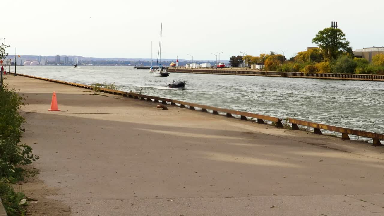 несколько лодок, идущих и проплывающих по каналу в гавань в ясный день, с городским пейзажем и горизонтом вдали