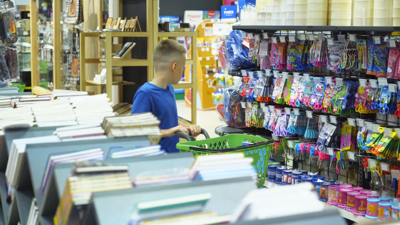 VINNITSA, UKRAINE - AUGUST 20, 2018: Beautiful boy choosing school stationery at a supermarket. Shopping for school