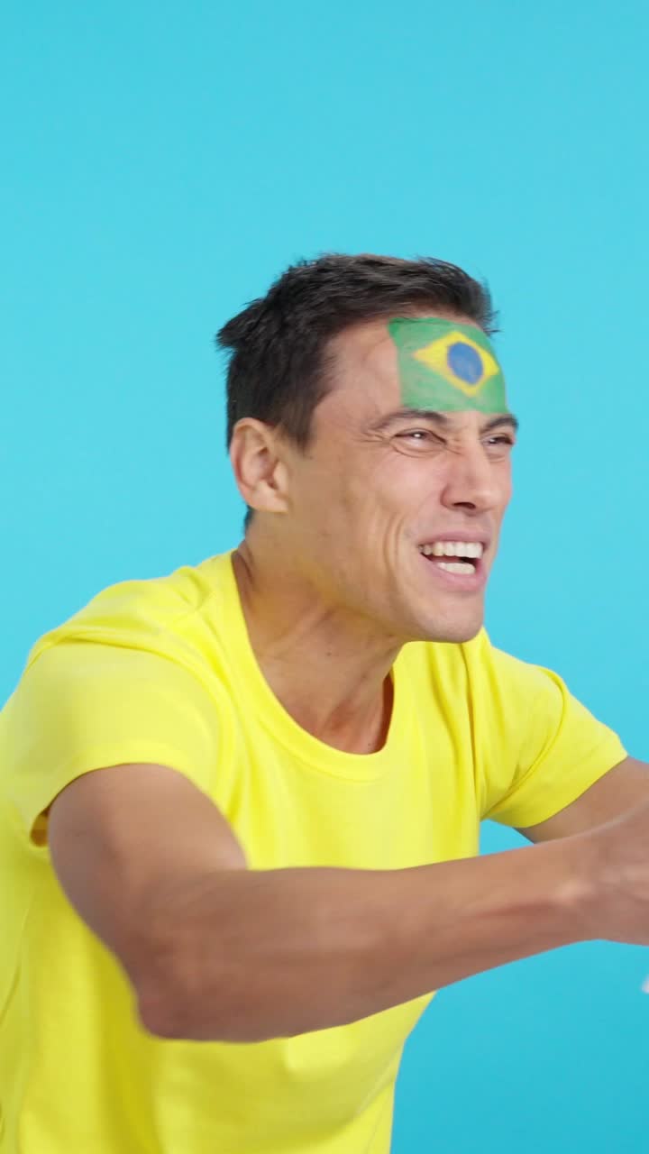 Brazilian supporter screaming and waving a national flag looking away